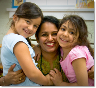 montessori teacher playing with two smiling girl kindergarten students